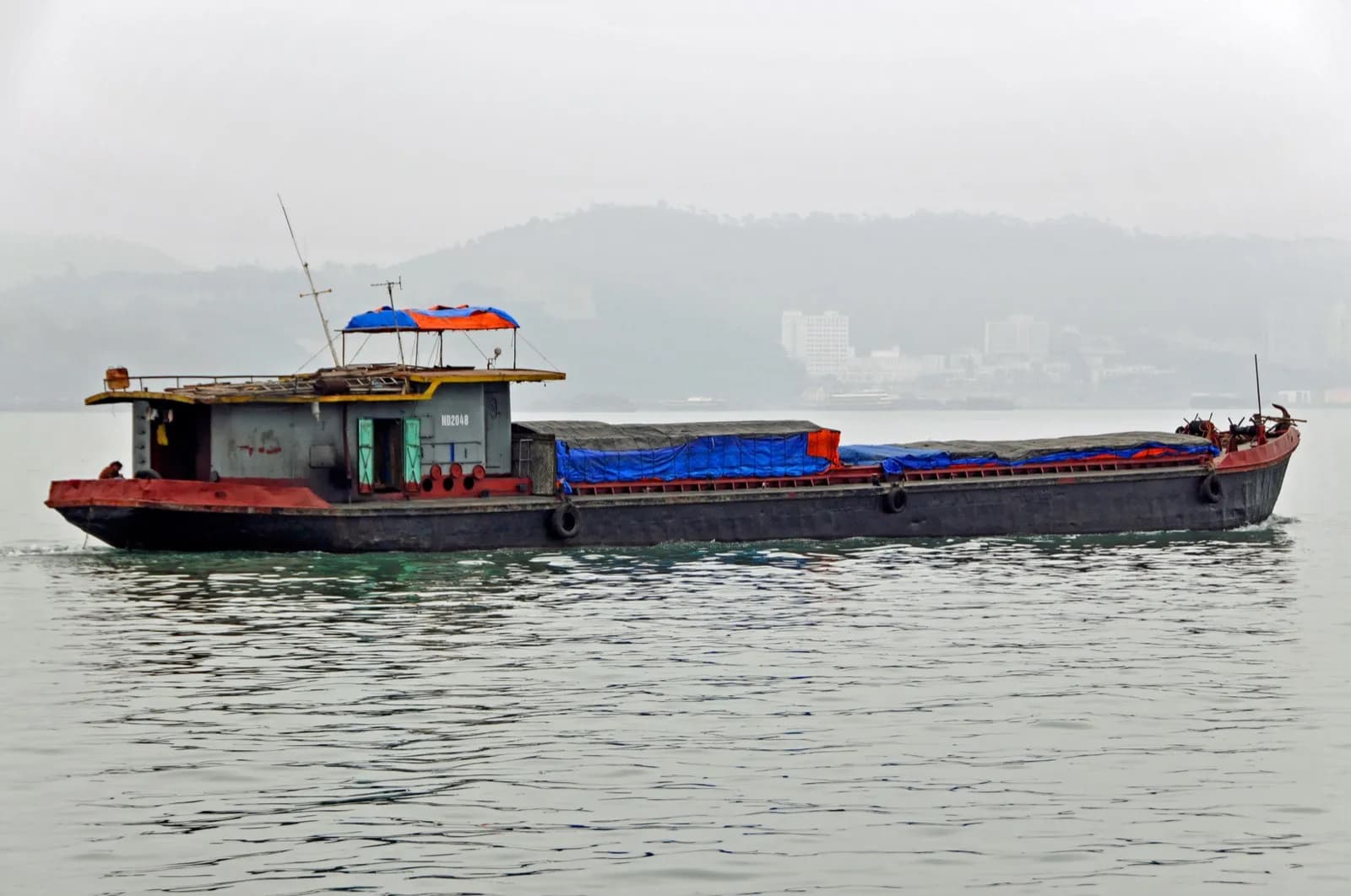 Sà lan chở than trên vịnh Hạ Long, phía sau là bờ Hạ Long – Hòn Gai